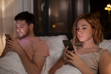 Image showing couple using smartphones in bed at night at home