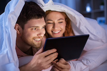 Image showing happy couple using tablet pc in bed at night