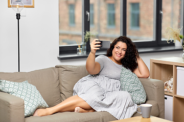 Image showing happy woman taking selfie with smartphone at home