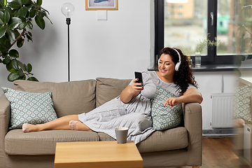 Image showing woman in headphones listens to music on smartphone