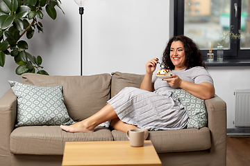 Image showing smiling young woman eating cake at home