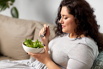 Image showing smiling young woman eating vegetable salad at home