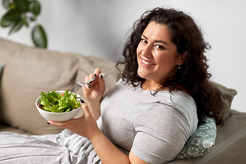 Image showing smiling young woman eating vegetable salad at home