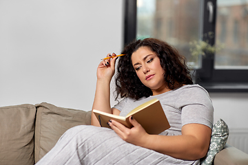 Image showing young woman with diary on sofa at home