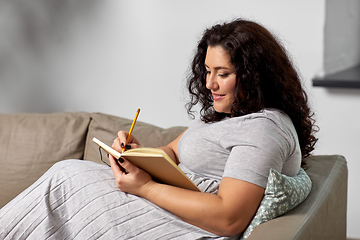 Image showing happy young woman with diary on sofa at home