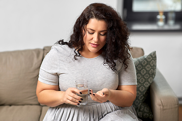 Image showing woman taking medicine with water at home