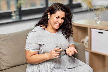 Image showing woman with cod liver oil pills and water at home