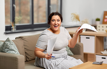Image showing happy woman with papers and calculator at home