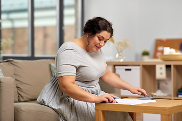 Image showing woman with papers and calculator working at home