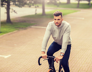 Image showing young man riding bicycle on city street