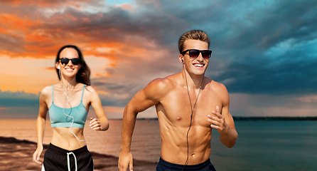 Image showing couple with earphones running over sea