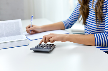 Image showing student girl counting on calculator at home