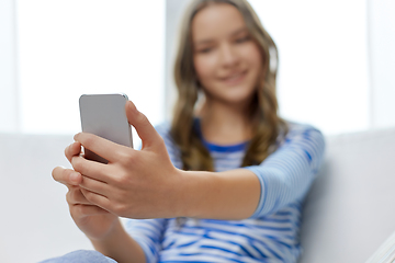 Image showing smiling teenage girl using smartphone at home