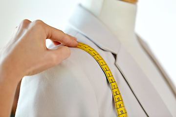 Image showing fashion designer measures jacket with tape measure