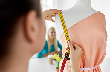 Image showing fashion designer measuring dress with tape measure