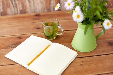 Image showing herbal tea, notebook and flowers in jug on table