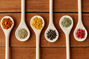 Image showing spoons with different spices on wooden table