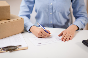 Image showing close up of woman filling postal form at office