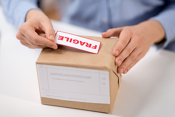 Image showing woman sticking fragile mark to parcel box