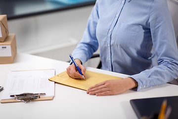 Image showing woman writing on parcel envelope at post office