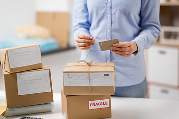 Image showing woman packing parcel and tying tag at post office