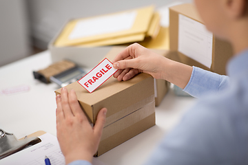 Image showing woman sticking fragile mark to parcel box