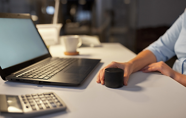 Image showing hand using smart speaker at night office