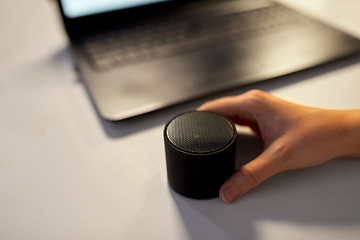 Image showing hand using smart speaker at night office