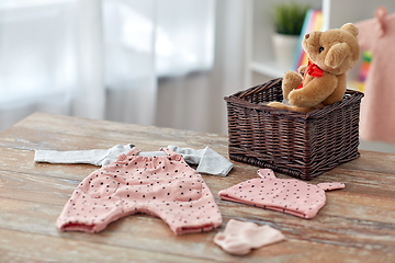 Image showing baby clothes and teddy bear toy in basket at home