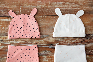 Image showing baby hats with ears and bibs on wooden table