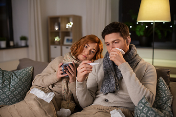 Image showing sick couple with thermometer and tea at home