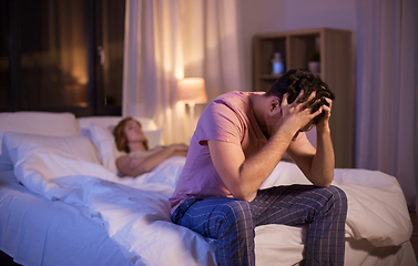 Image showing sad man with insomnia sitting on bed at night