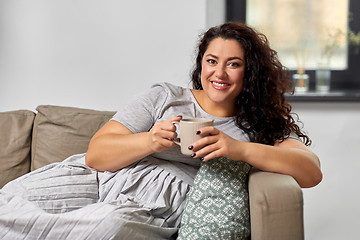 Image showing happy woman drinking coffee or tea on sofa at home