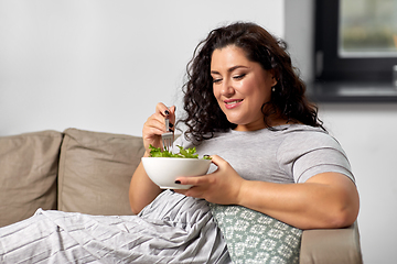 Image showing smiling young woman eating vegetable salad at home