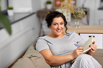 Image showing happy young woman with diary on sofa at home