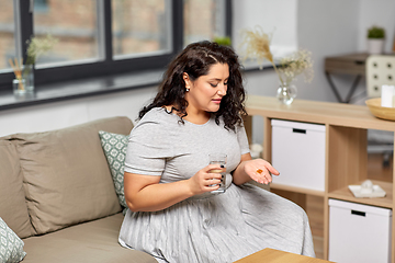 Image showing woman with cod liver oil pills and water at home