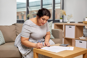 Image showing woman with bills or papers and calculator at home