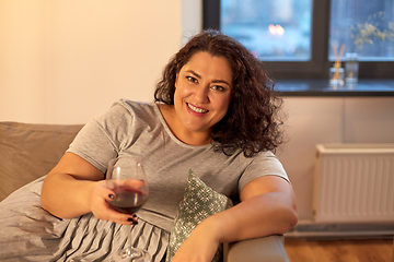 Image showing happy woman drinking red wine at home in evening