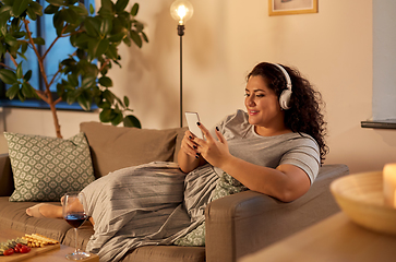 Image showing woman in headphones listens to music on smartphone