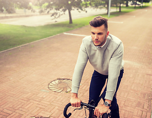 Image showing young man riding bicycle on city street