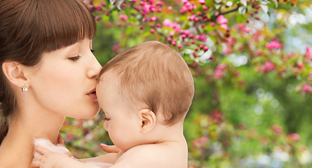 Image showing close up of happy mother kissing baby over garden