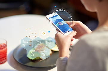 Image showing hands with phone and food nutritional value chart