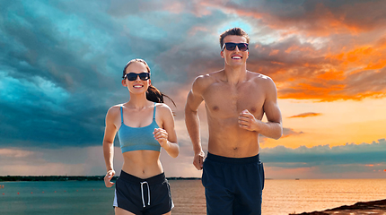 Image showing couple in sports clothes running along on beach