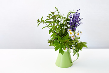 Image showing bunch of herbs and flowers in green jug on table