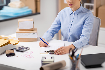 Image showing woman with clipboard and parcels at post office