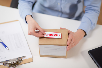 Image showing woman sticking fragile mark to parcel box