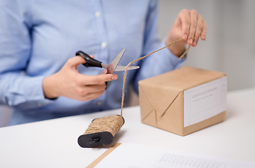 Image showing woman with parcel cutting rope at post office