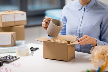 Image showing woman packing mug to parcel box at post office