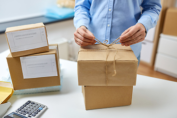 Image showing woman packing parcel and tying rope at post office