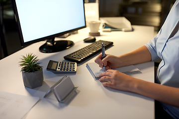 Image showing businesswoman writing to notebook at night office